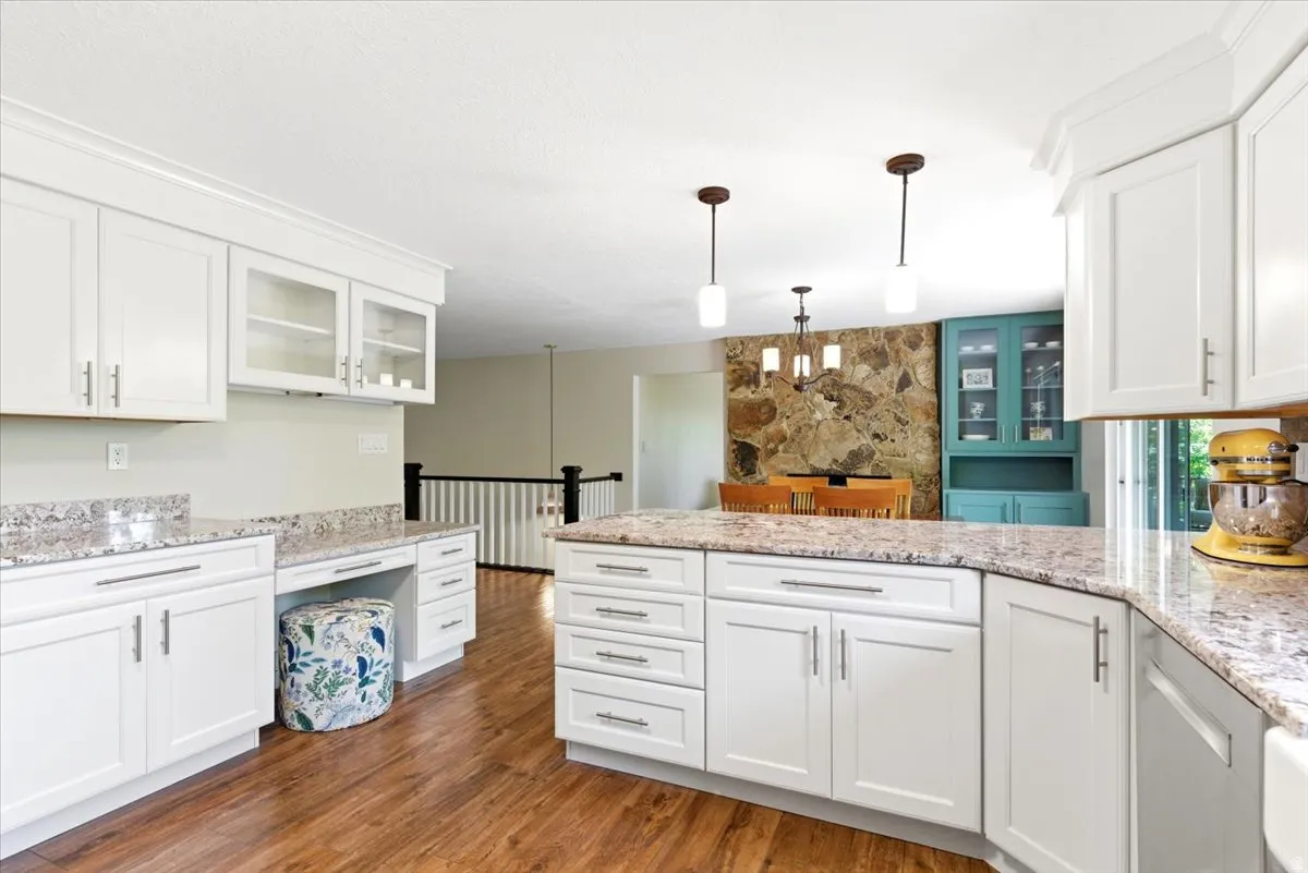 Updated kitchen with beautiful granite countertops, white shaker cabinets, 5 burner gas range, large basin farmhouse sink, & glass tile backsplash