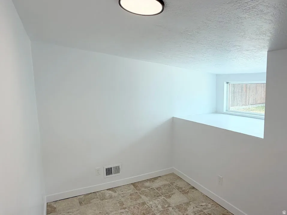 Interior room featuring white walls, a single window, and tiled flooring