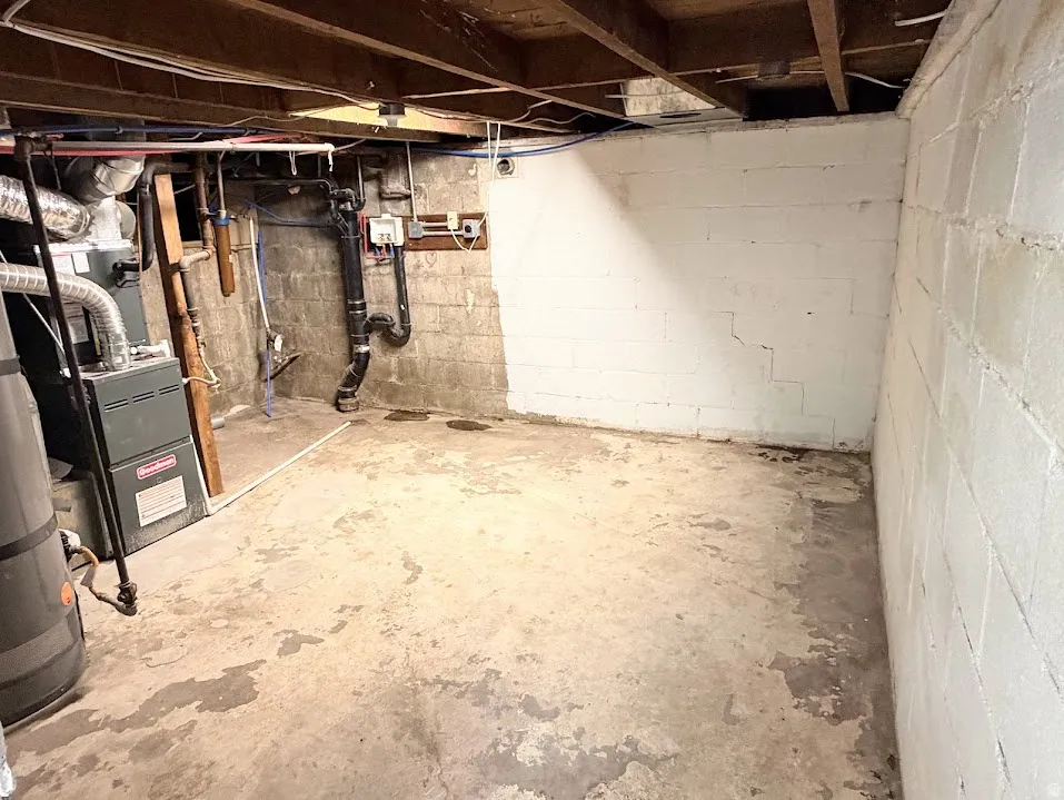 Unfinished basement space with exposed ceiling joists and concrete block walls