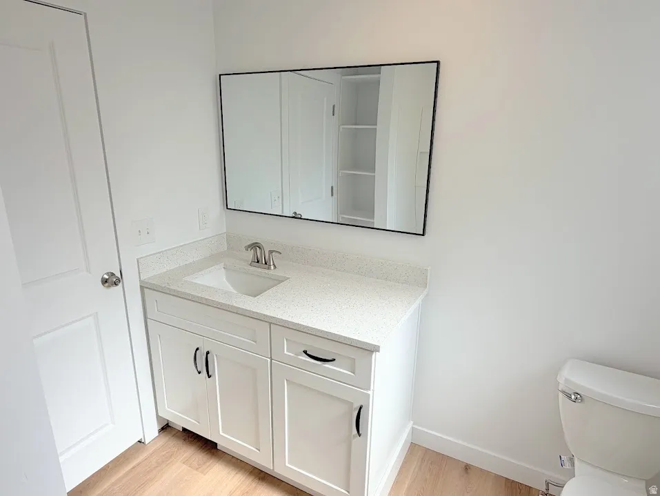 White shaker-style vanity with black hardware, white speckled countertop, and undermount sink