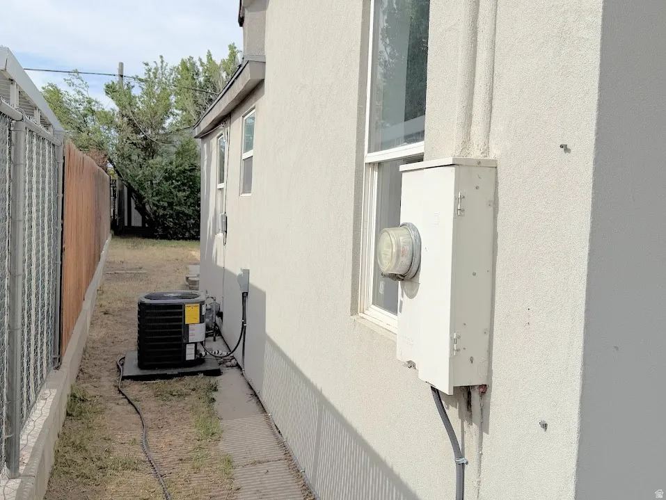 Exterior stucco siding with a visible electrical meter and an HVAC unit on a concrete pad