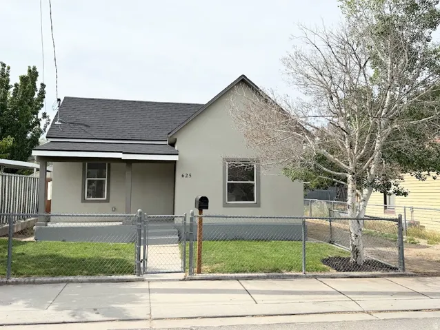 Neutral-toned stucco exterior with a dark shingle roof and white trim windows