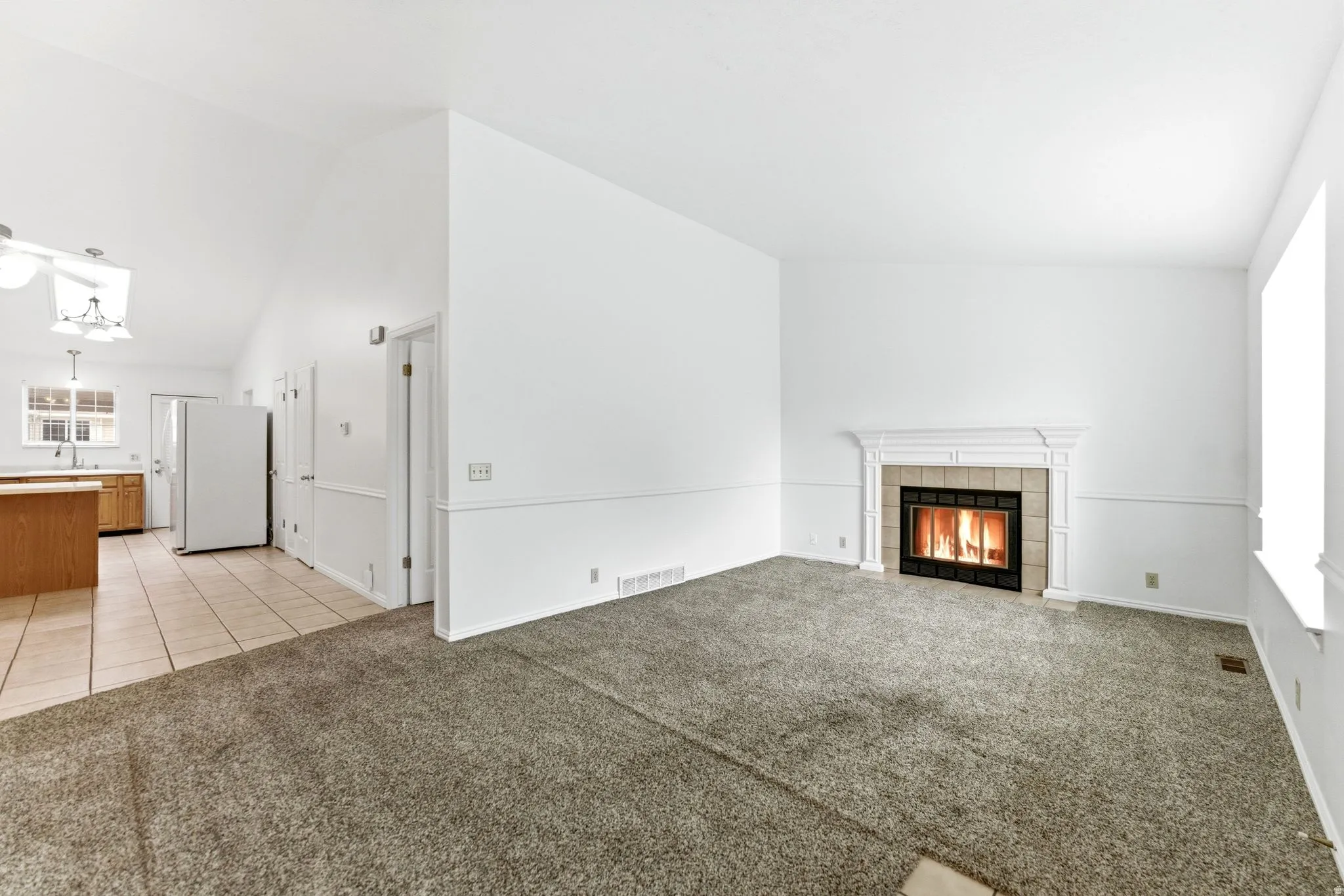 Living area featuring a fireplace with a decorative mantel, carpet flooring, and a window with white trim