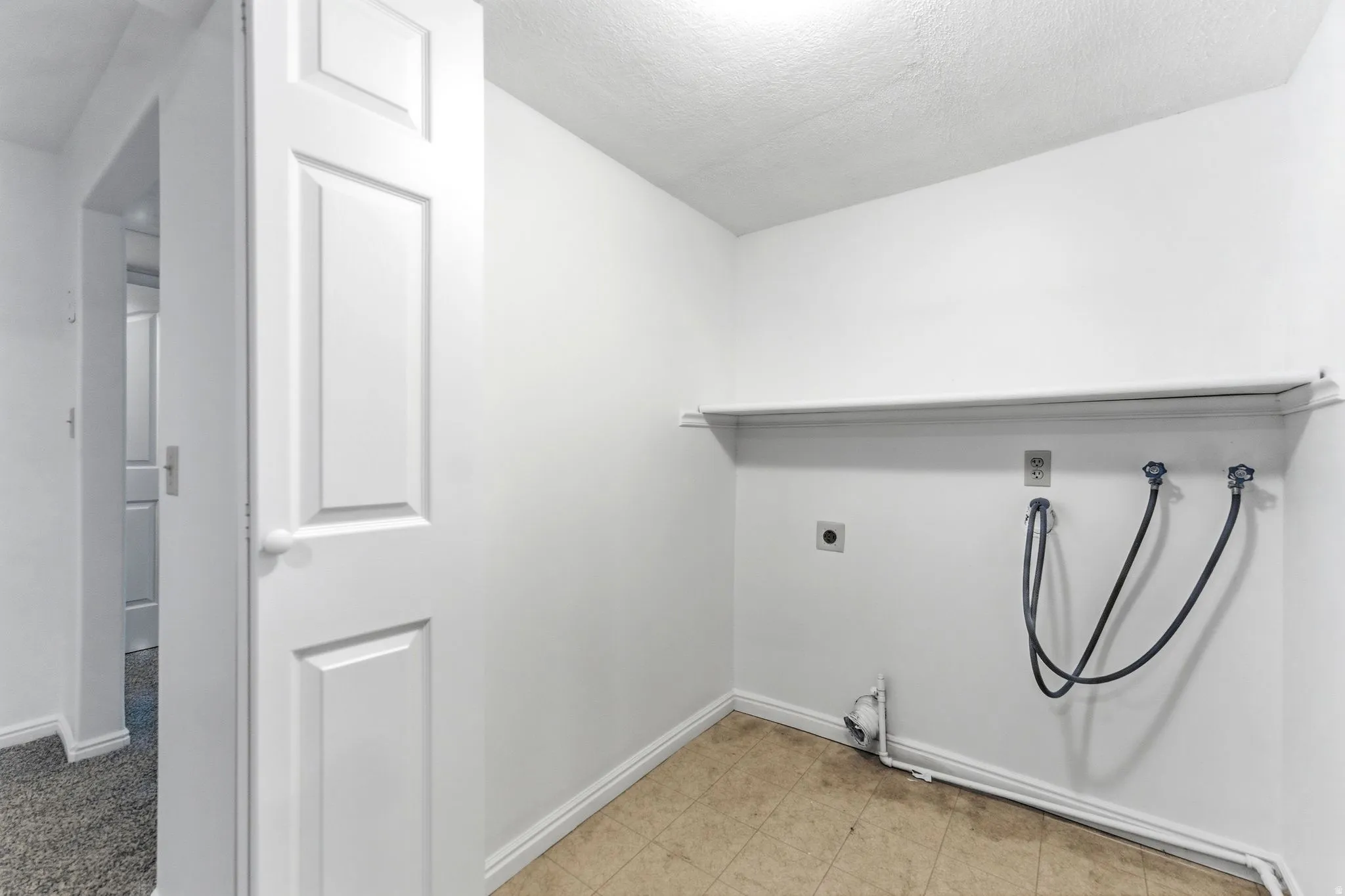Dedicated utility space featuring a built-in shelf, appliance hookups, white baseboards, and neutral-toned flooring