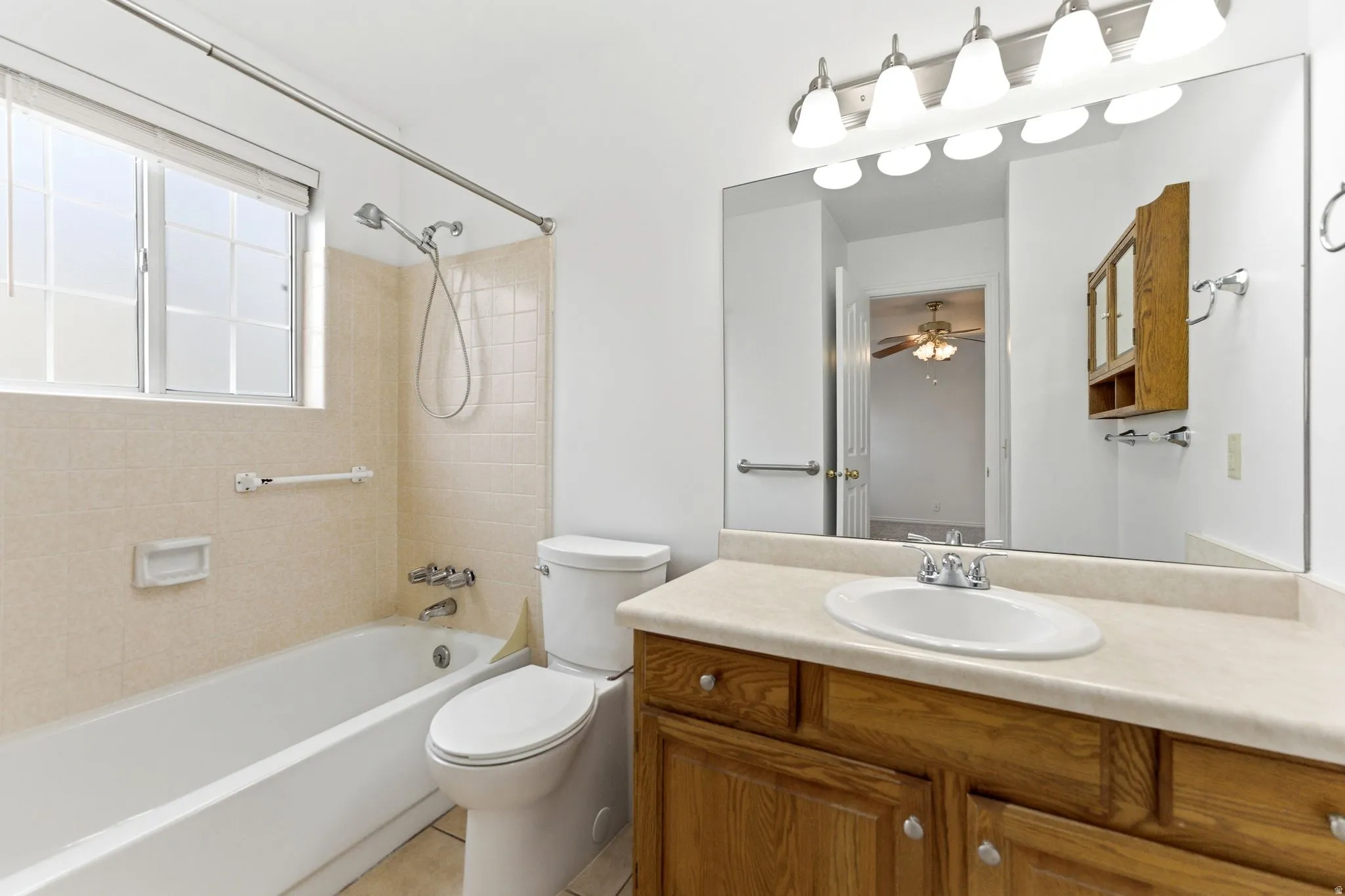 Bathroom featuring a full vanity with a wooden base, a white drop-in sink, and a large mirror