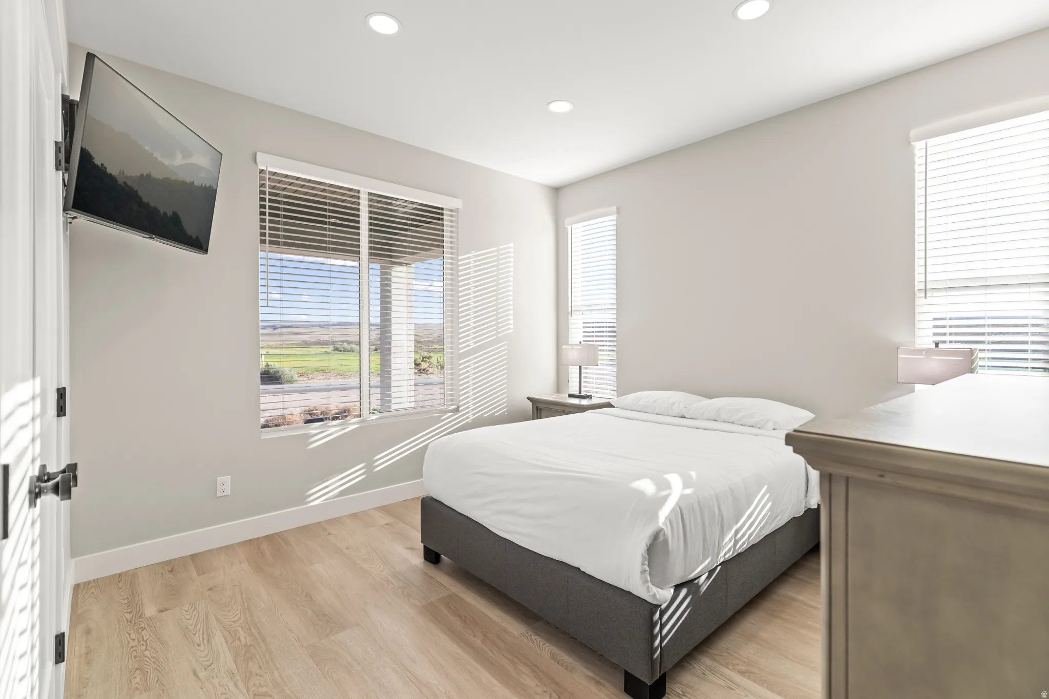 Wood-finish flooring throughout, complemented by recessed lighting and multiple windows with blinds