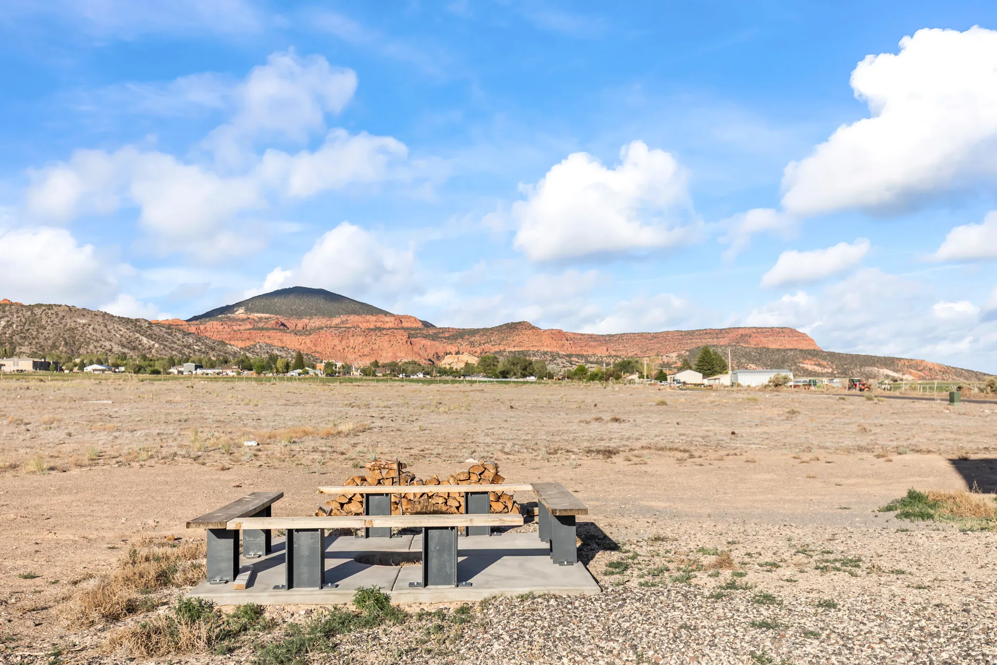 Outdoor seating area with integrated fire pit, positioned on a gravel and dirt lot