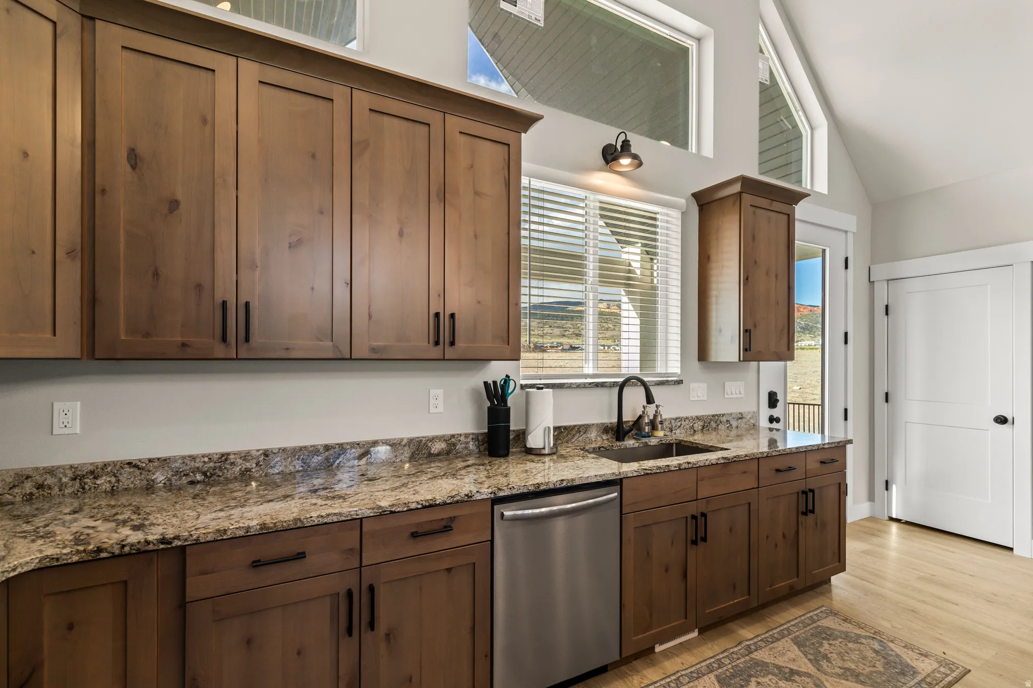 Kitchen featuring wood-finish cabinetry, speckled countertops, stainless steel appliances, and a stainless steel sink with a matte black faucet