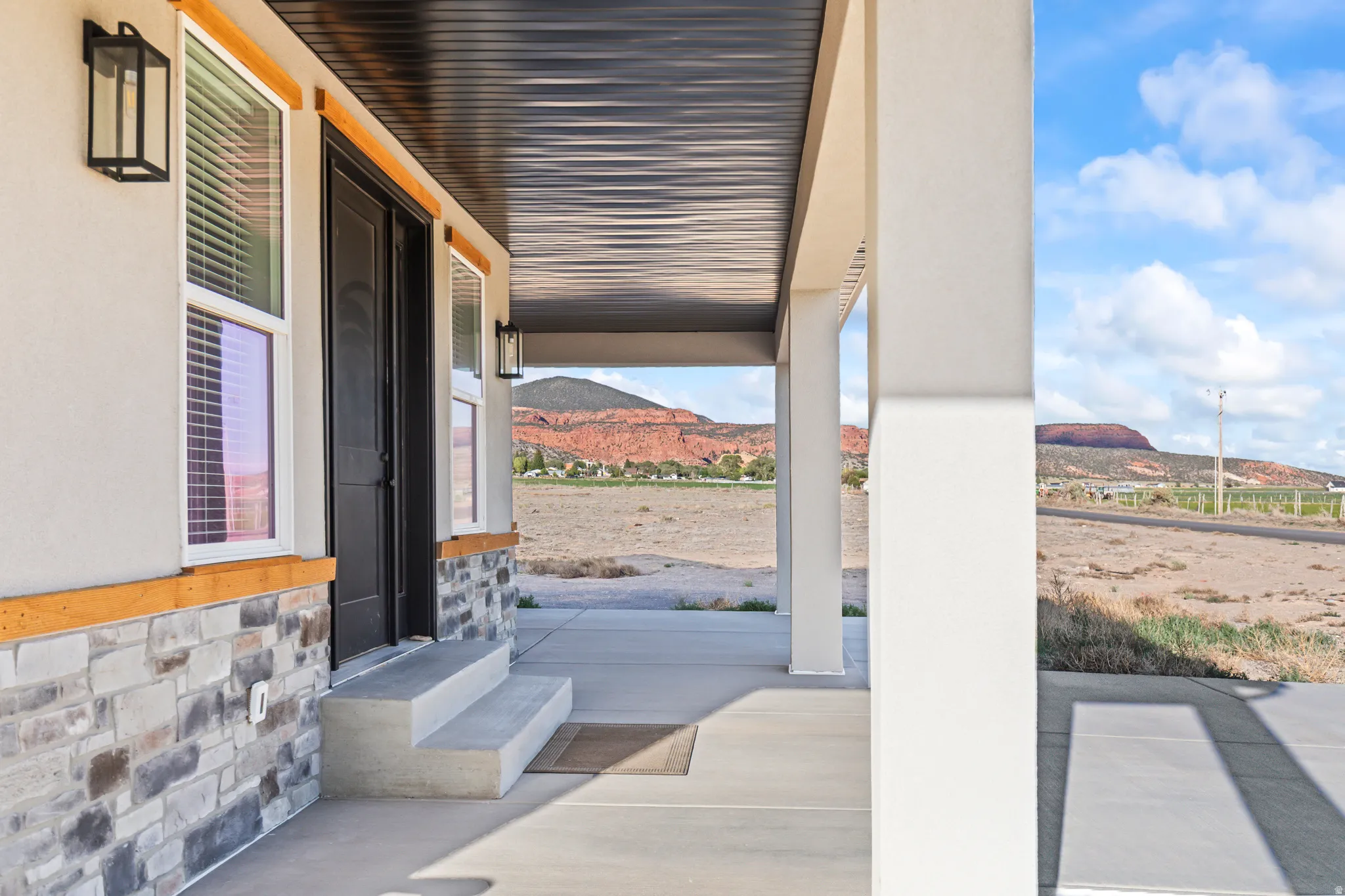 Covered front porch featuring concrete flooring and steps