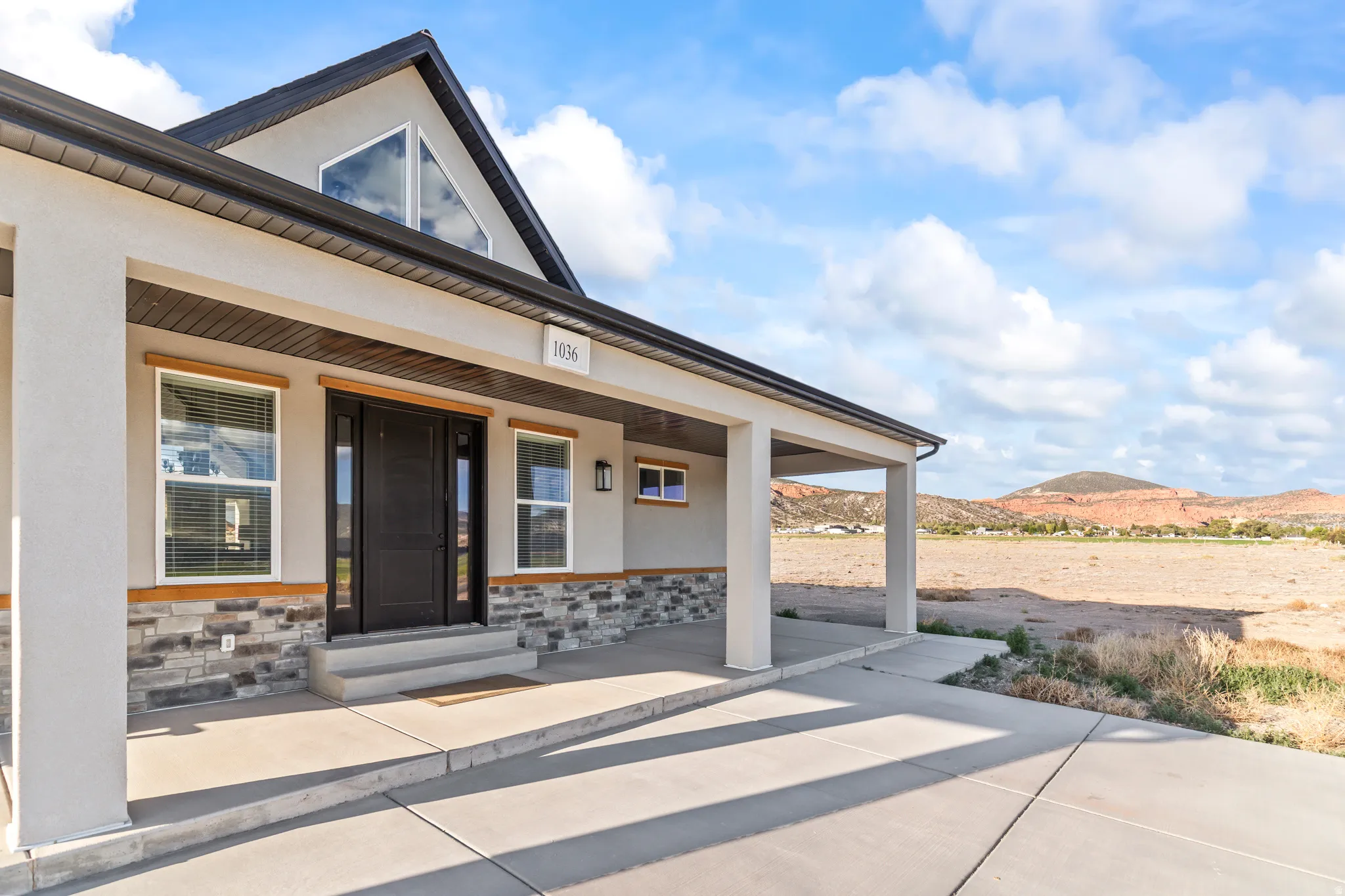 Modern exterior with a covered porch, dark entry door, and stone veneer accents