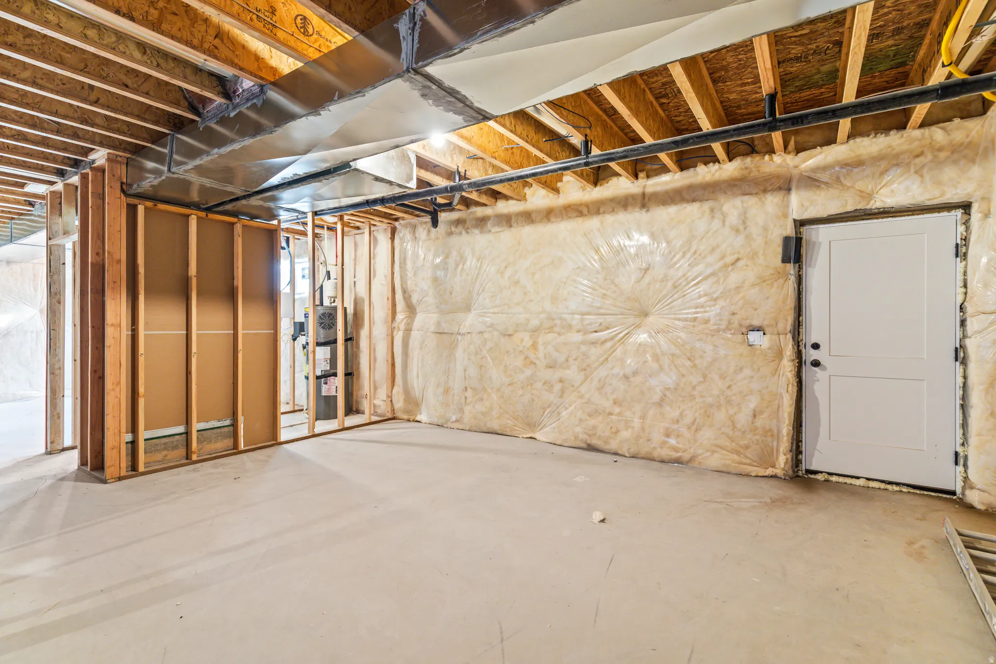 Unfinished basement featuring exposed wood joists, concrete flooring, and insulated walls