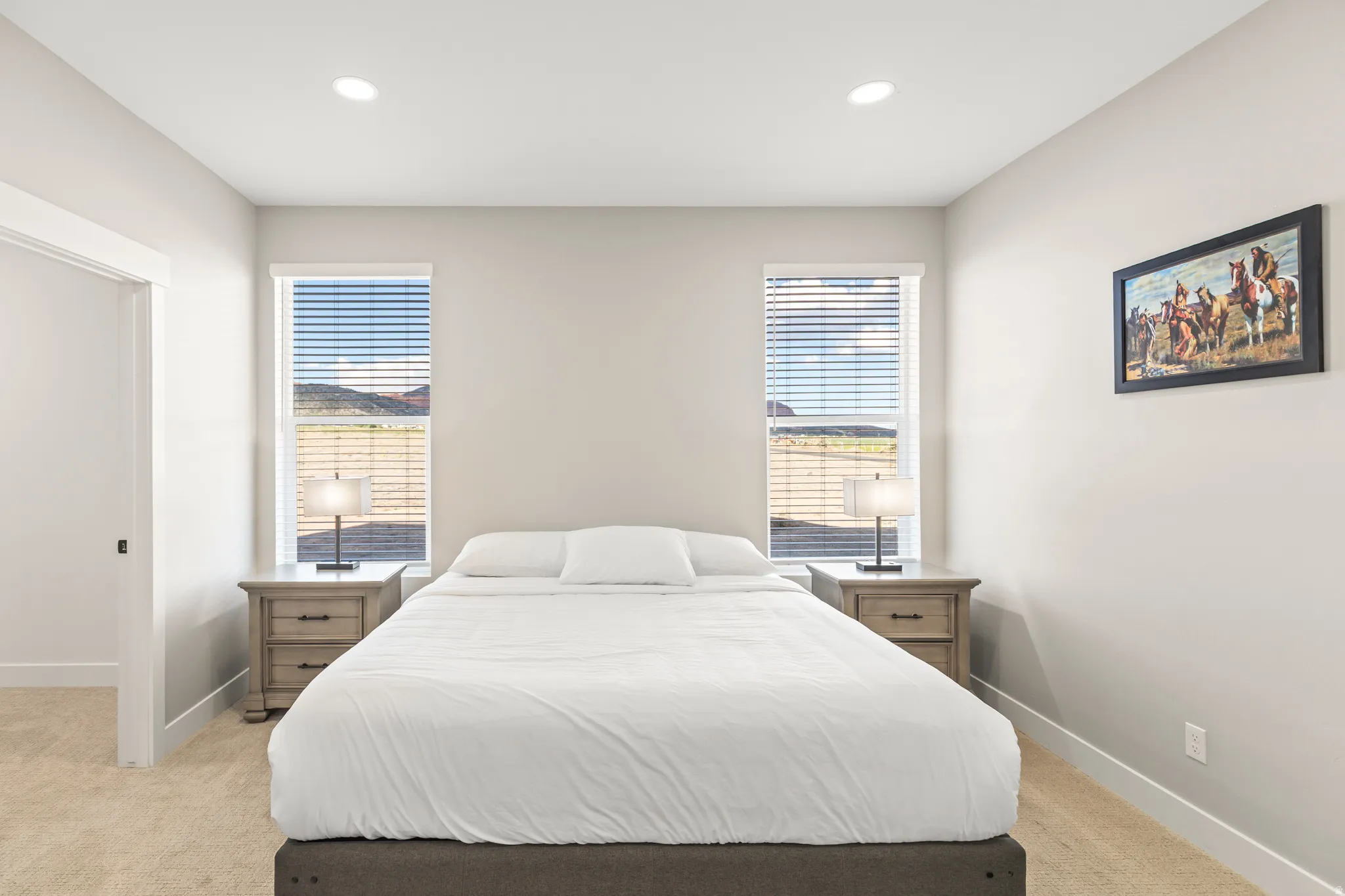 Neutral-toned bedroom featuring two windows with blinds, recessed lighting, and light-colored carpeting