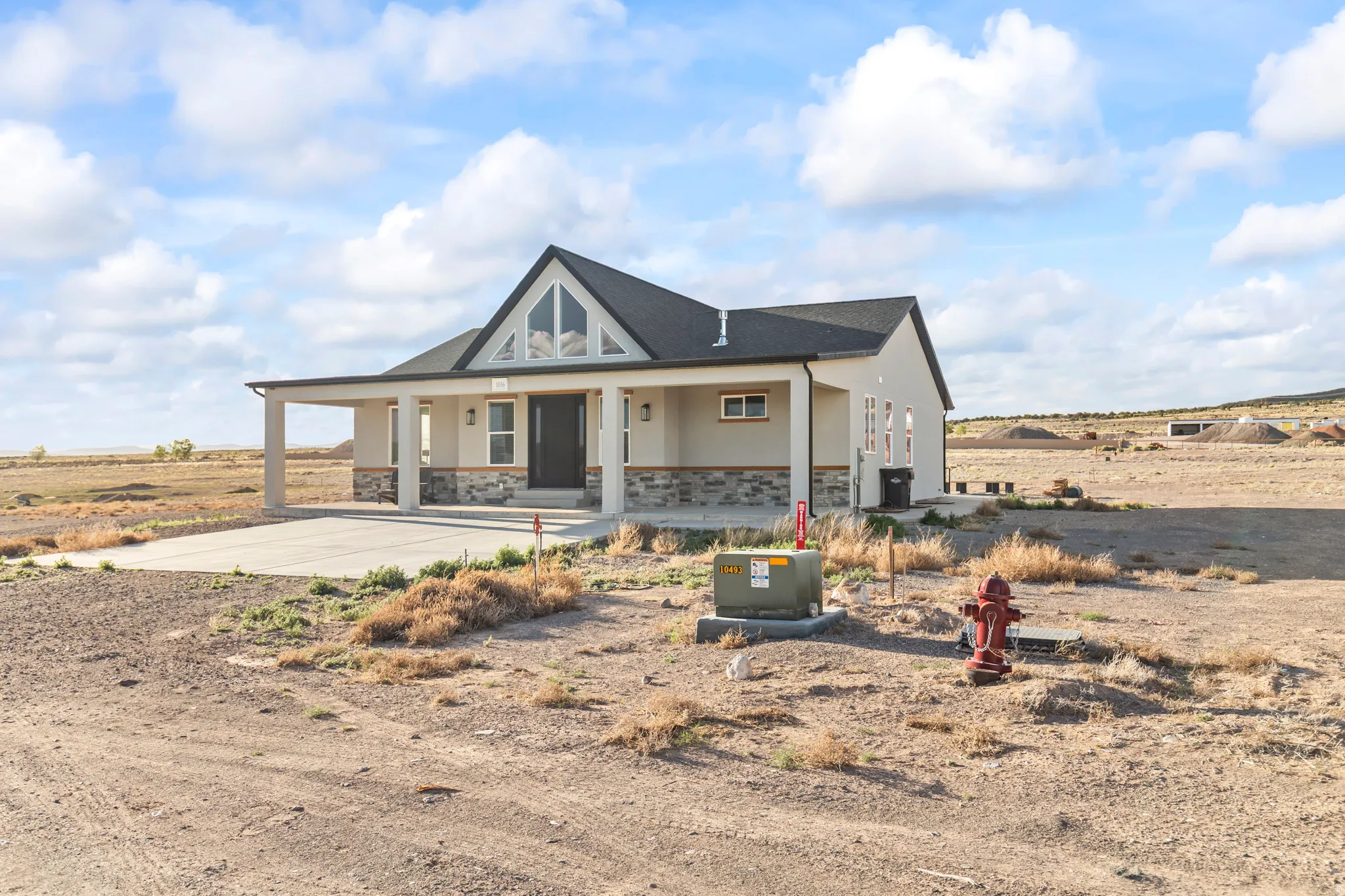 Contemporary single-story residence featuring a covered front porch, stone accent siding, and a dark asphalt shingle roof