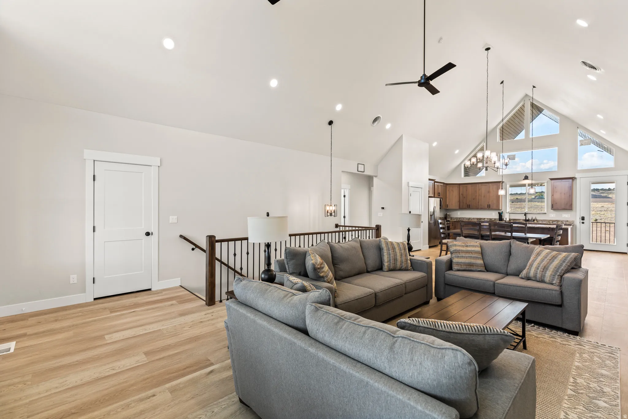 Vaulted ceilings with recessed lighting and a ceiling fan enhance this open-concept living space