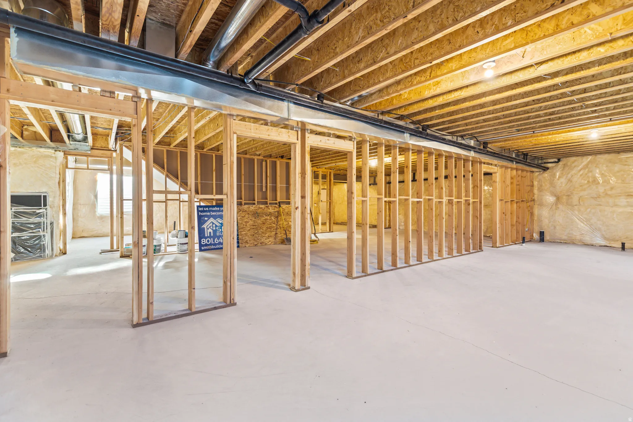 Unfinished basement space featuring visible wood framing, concrete flooring, exposed ceiling joists, and installed ductwork