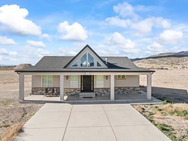 Modern home with an expansive covered front porch, stone veneer siding, and a striking gable with large windows