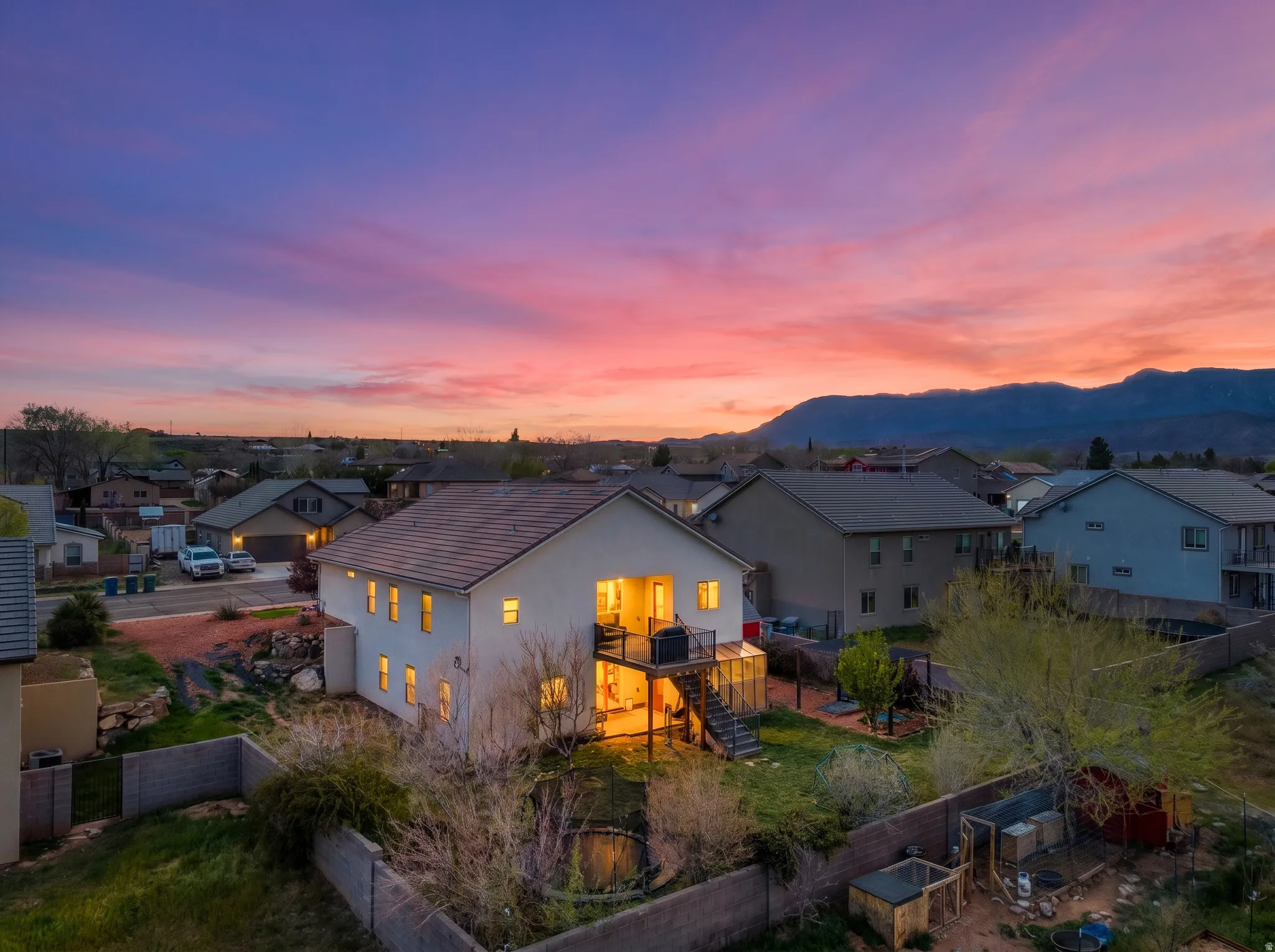 Two-story property featuring a rear deck with an outdoor grill, ground-level sunroom, and a fully fenced backyard
