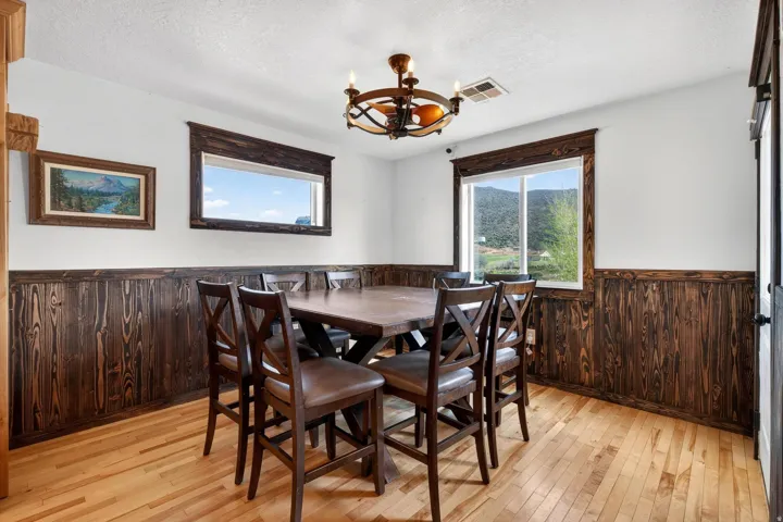 Room featuring light wood-finish flooring, dark wood-paneled wainscoting, and white painted walls