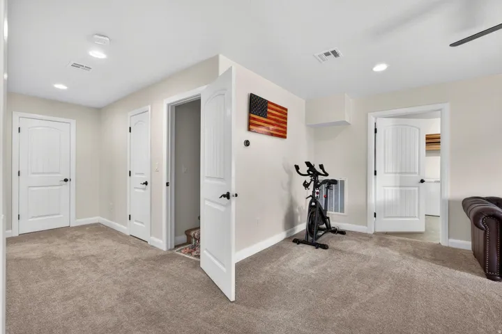 Spacious interior room featuring light neutral wall paint, recessed lighting, and soft brown carpeting