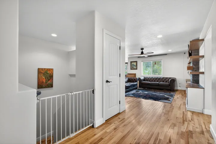 Hardwood flooring extending through the living area, featuring a ceiling fan and recessed lighting