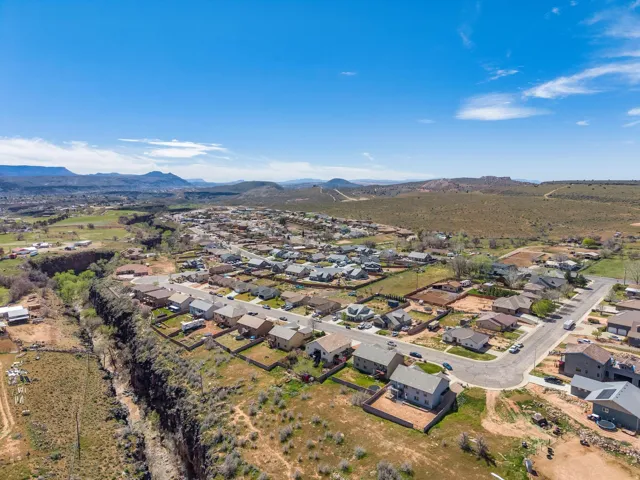 Residential neighborhood with detached homes, surrounded by natural desert landscape and distant mountains under a clear sky