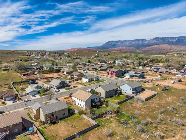 Aerial overview of a residential neighborhood with distant mountain ranges and red rock formations