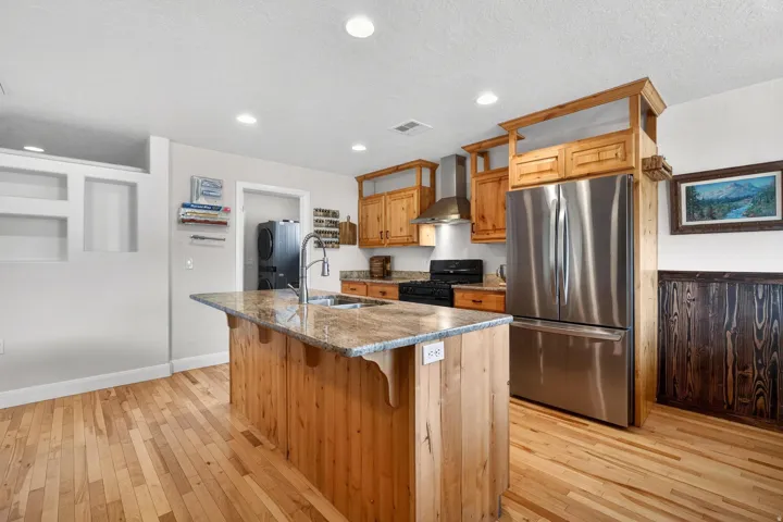 Kitchen featuring a central island with a granite countertop, light wood-finish flooring, recessed lighting, stainless steel appliances, and wood cabinetry