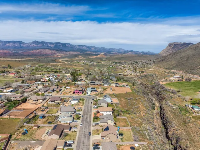 Aerial perspective showcasing a residential community nestled within a valley, bordered by mountainous terrain