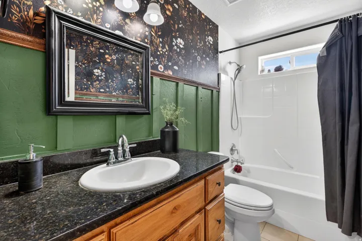 Vanity with an integrated white sink, dark countertop, and wood-finish cabinetry