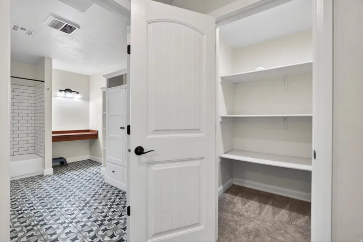 Bathroom with decorative floor tile, white subway tile shower surround, and a floating wood-finish vanity