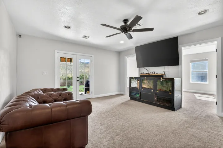 Spacious carpeted room featuring French doors, a ceiling fan, recessed lighting, and a built-in media console