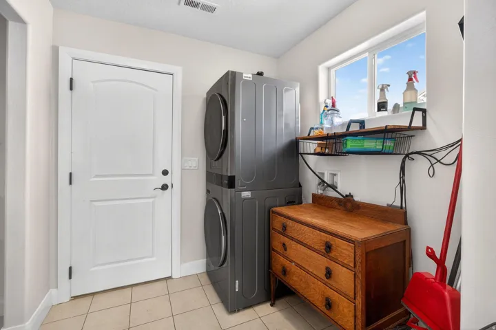 Dedicated utility space featuring light-colored tile flooring, a white paneled door with dark hardware, and a window providing natural illumination