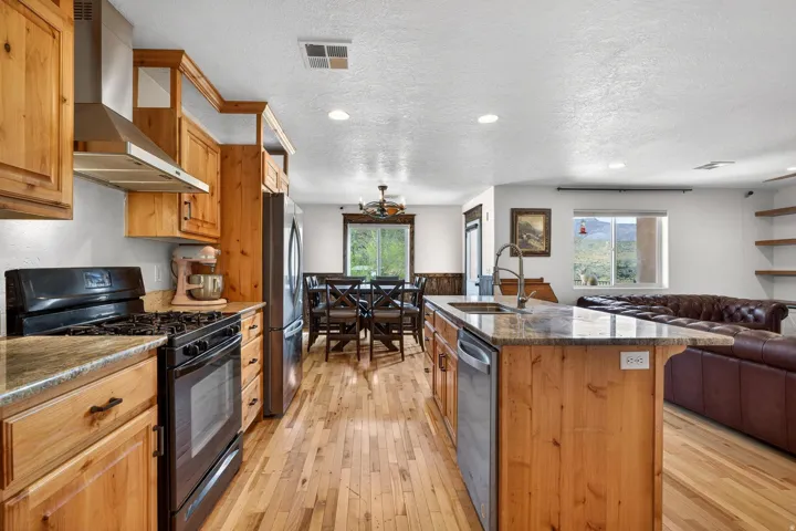 Open-concept kitchen featuring wood-finish cabinetry, stainless steel appliances, and an expansive island with a built-in sink and dishwasher