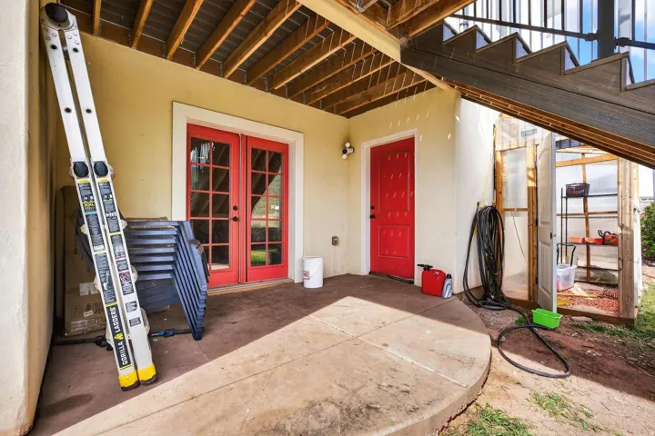 Covered patio with concrete flooring, featuring red French doors and a matching solid red door