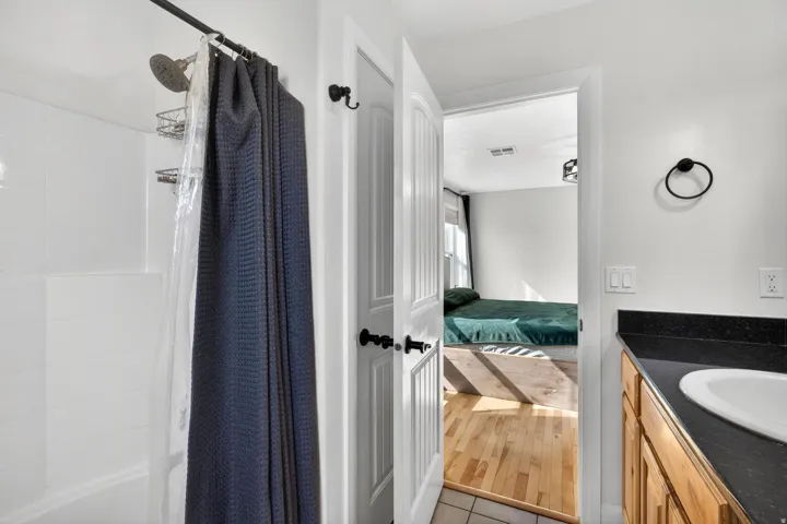 Bathroom featuring a white tub-shower combination with a chrome showerhead and a dark countertop vanity with an undermount sink