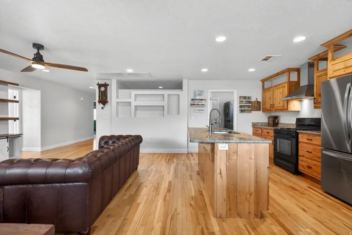 Open-concept living space featuring wood-finish flooring, recessed lighting, and a ceiling fan