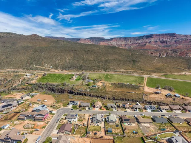 Aerial perspective showcasing a residential development with individual properties, verdant fields, and a distinct canyon feature