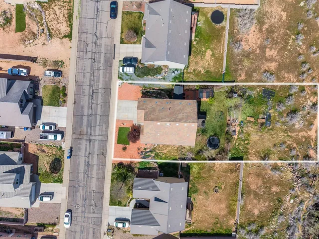 Property boundary encompassing a residential home with a partial paved driveway and an expansive rear yard featuring varied terrain