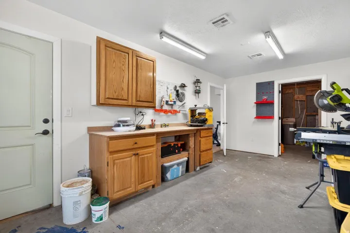 Dedicated workspace featuring a built-in wood-finish workbench with upper and lower cabinetry, providing ample storage and surface area