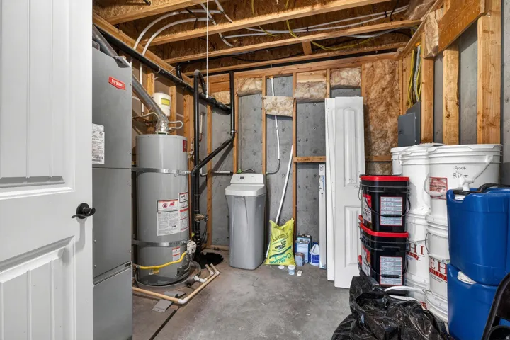 Utility space featuring a water heater, furnace, water softener, exposed wood framing, and a concrete floor