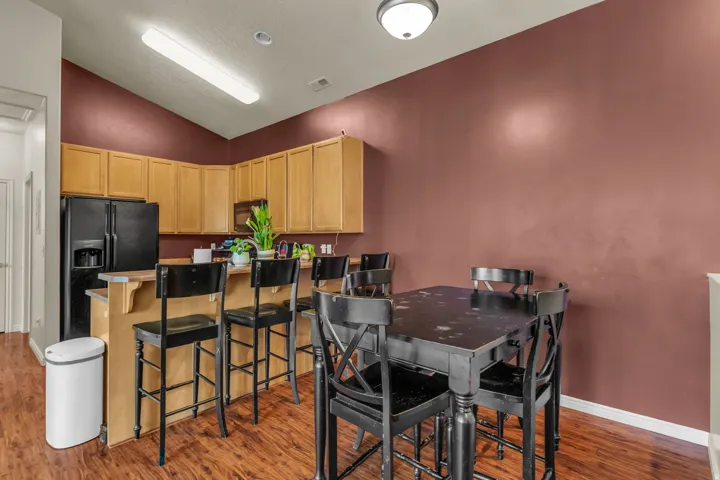 Kitchen featuring wood-finish flooring, light wood cabinetry, black appliances, and a breakfast bar