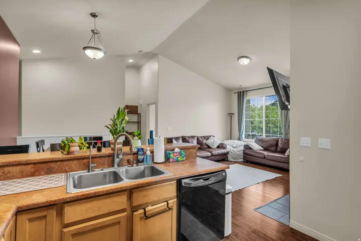 Kitchen with a double basin stainless steel sink, a black dishwasher, and warm wood-finish cabinetry