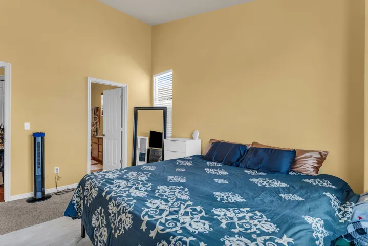 Carpeted room with vaulted ceilings and a transom window featuring blinds