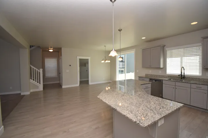 Open-concept living space featuring wood-finish flooring, a kitchen island with stone countertop, gray cabinetry, and stainless steel appliances