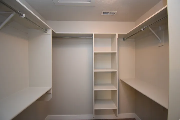 Walk-in closet featuring extensive built-in shelving, multiple hanging rods, and perimeter shelving