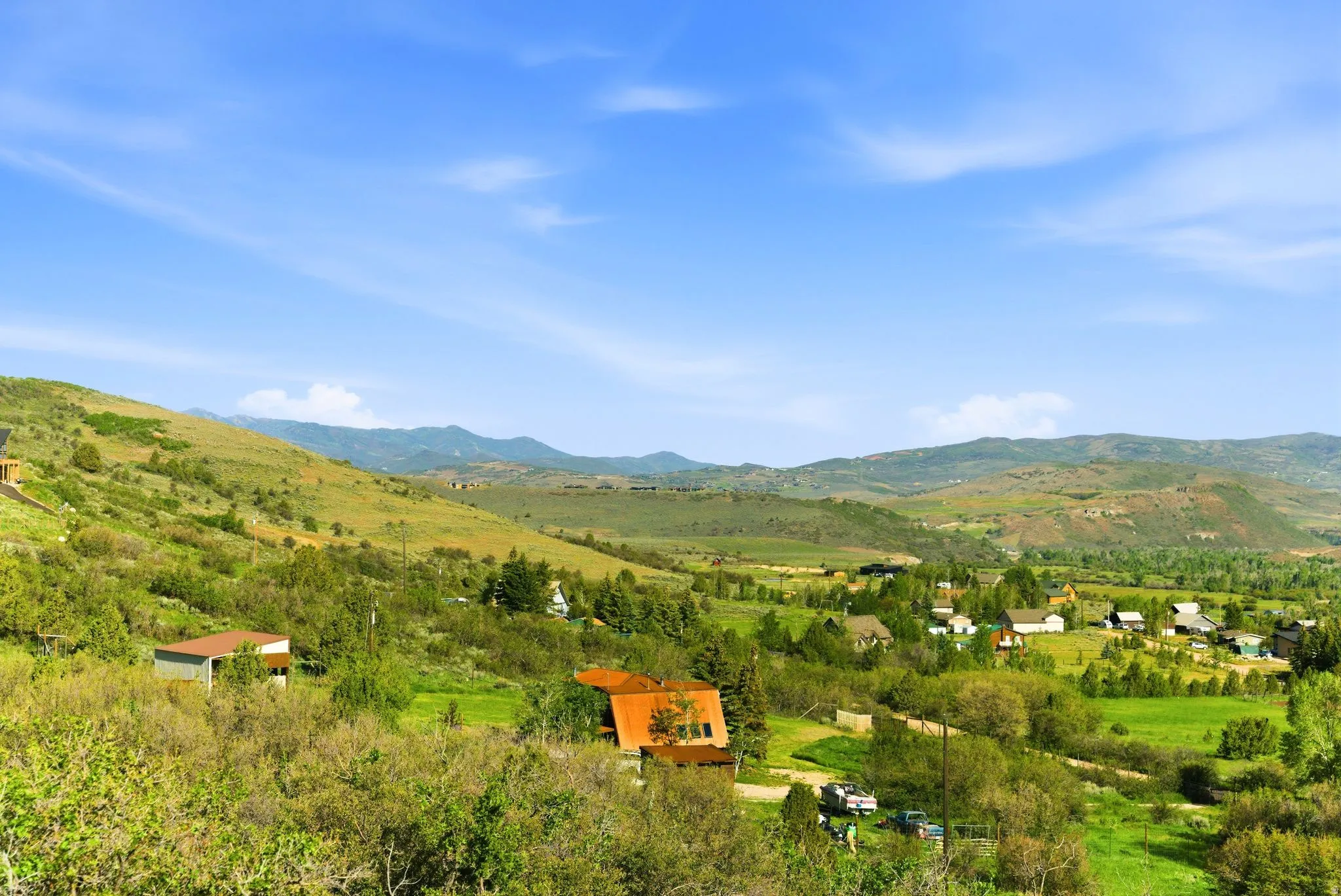 Expansive hillside setting with abundant natural vegetation and distant mountain ranges