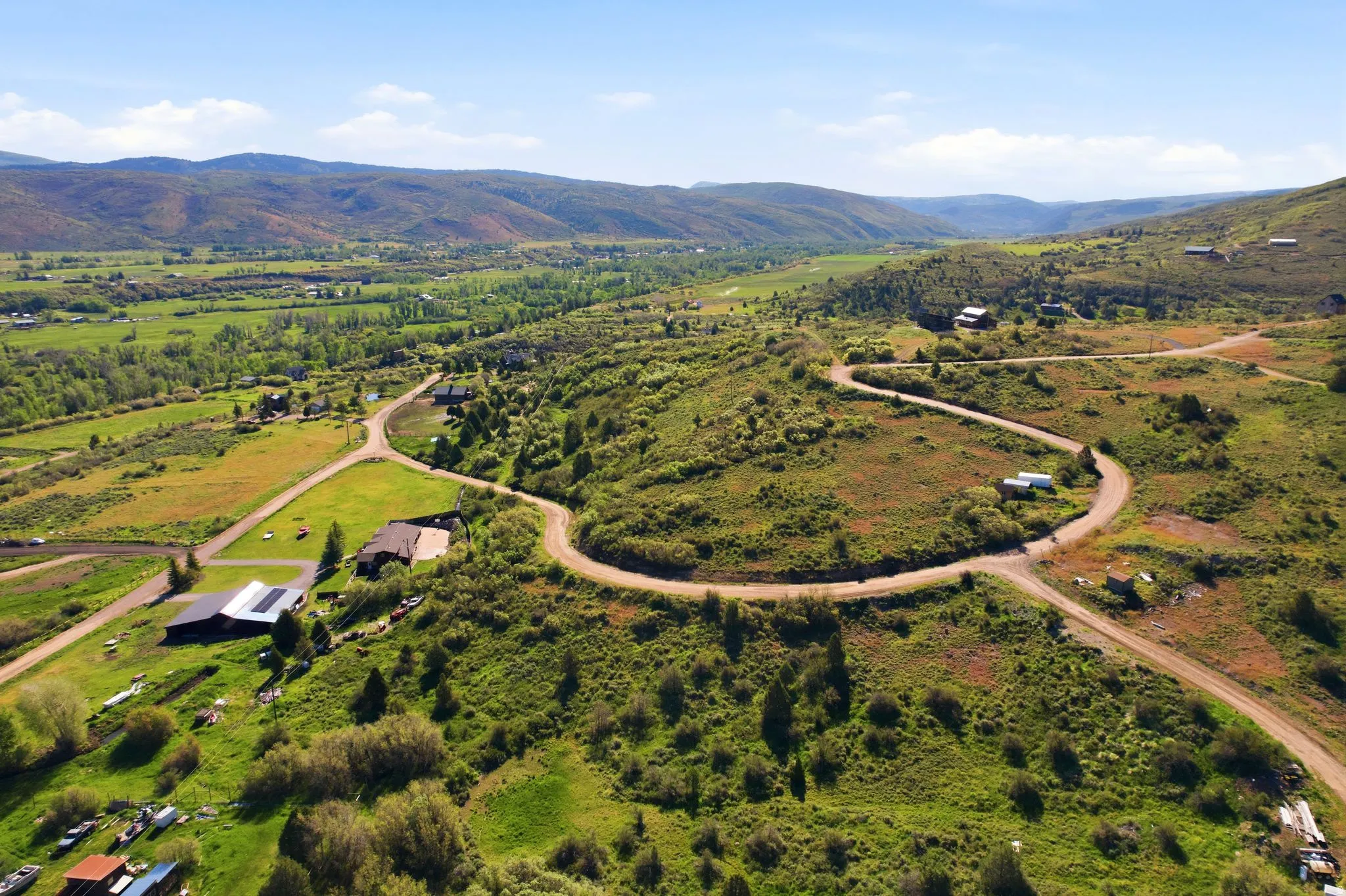 Expansive mountain valley landscape featuring winding roads and scattered residential properties