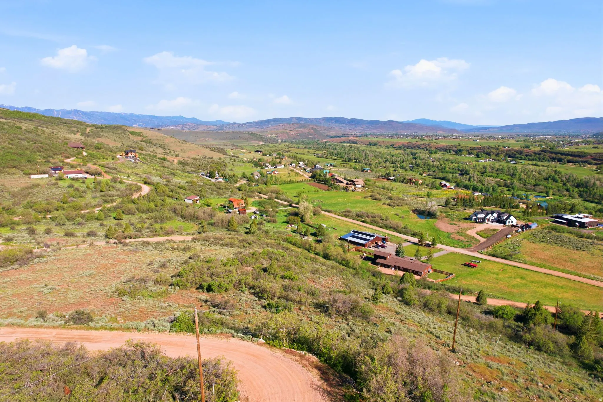 Expansive mountainous terrain featuring diverse vegetation and distant residential structures