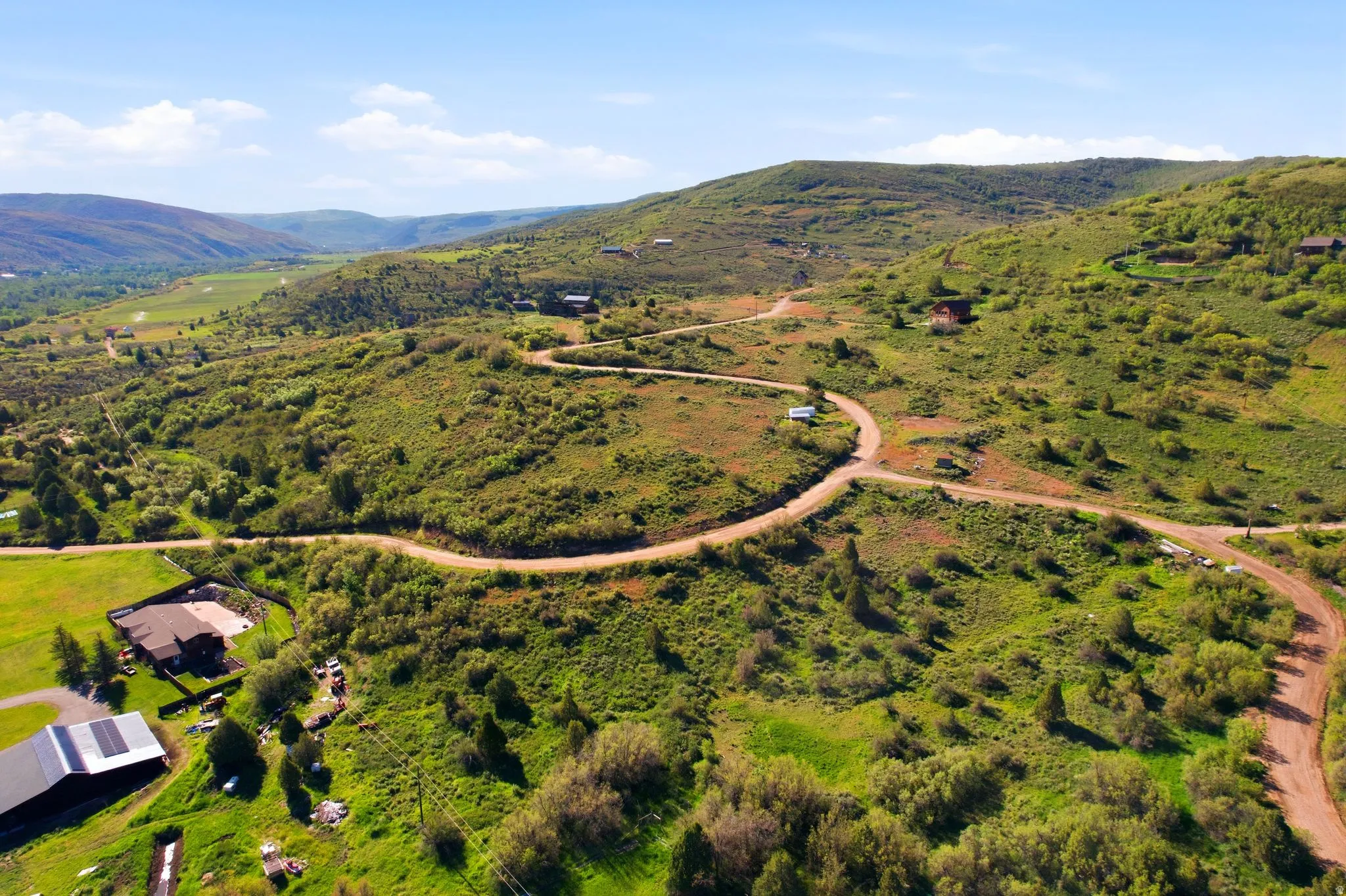 Expansive hillside terrain featuring verdant foliage and a winding dirt road