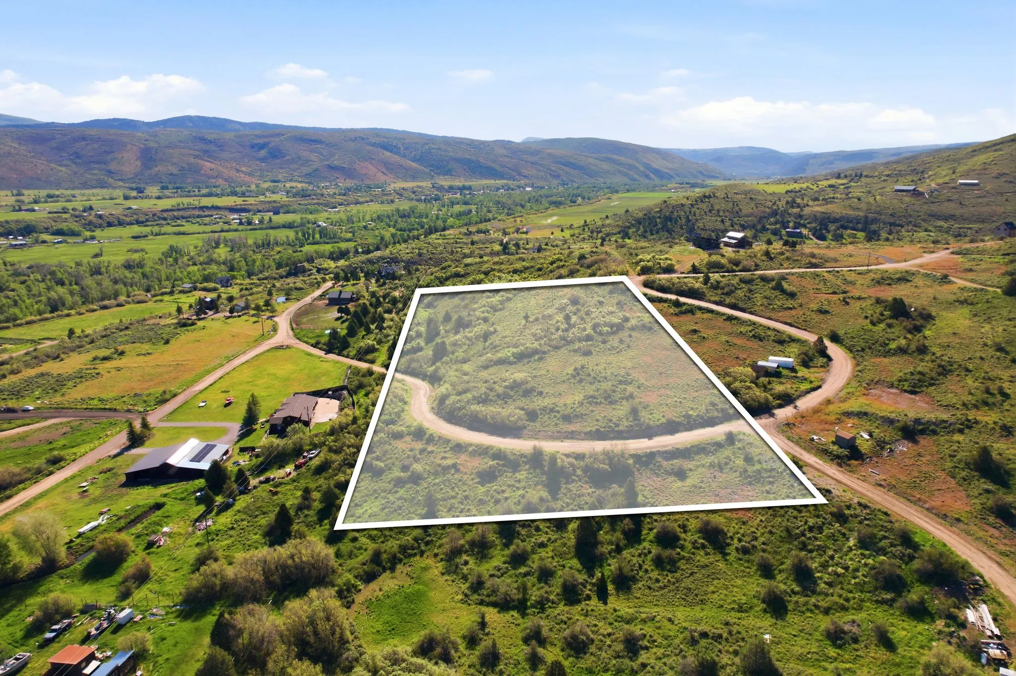 Expansive land parcel featuring natural terrain and a winding dirt road